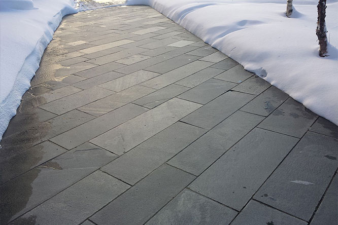 Heated stone walkway in winter with snow on the sides